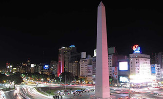 Obelisco de 9 de Julio de noche, iluminado por los letreros y las luces de los autos